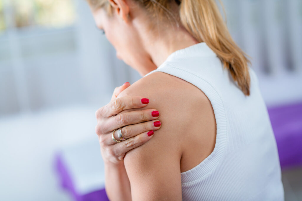 Woman holding her shoulder due to shoulder pain before seeking treatment at iGood Health Centre in Richmond Hill
